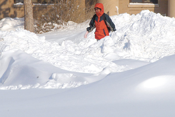 A student waks around the large piles of snow on the East Campus mall Feb. 2 between classes. Several storms...