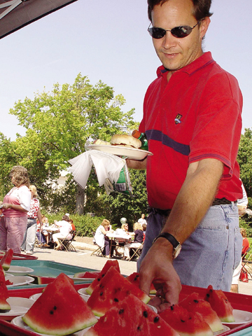 Gary Kimminau, assistant manager of Information Services, takes a slice of watermelon at the all-university picnic, which followed Chancellor Harvey...