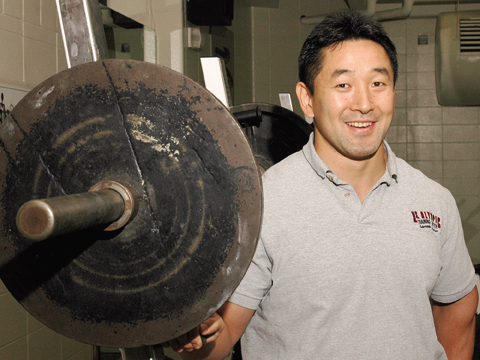 Shinya Takahashi, coordinator for strength and conditioning at UNL Campus Recreation, stands next to a set of free weights. A...