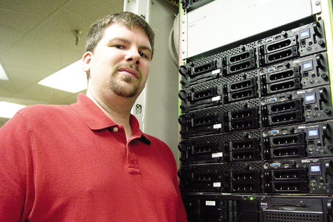 Zac Reimer, network security analyst for Information Services, stands next to a handful of the servers that handle e-mail traffic...