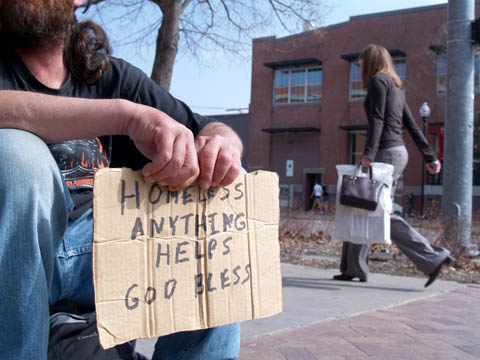 CARDBOARD REQUEST - Tim, a 44-year-old homeless man, holds a cardboard sign as an individual walks by in downtown Lincoln...