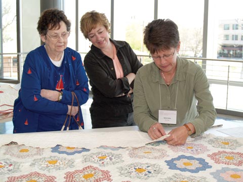 QUILT STUDY - (From left) Beulah and Laurie Bellows watch as Karla Salda, an IQSC volunteer, sews a muslin documentation label...