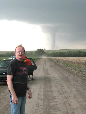 STORM MOMENT - Ken Dewey poses for a photo with a tornado during a May 29 storm chase in central Nebraska...